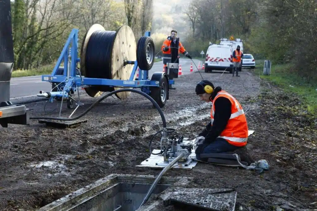 Technicien déployant un câble de fibre optique en bord de route